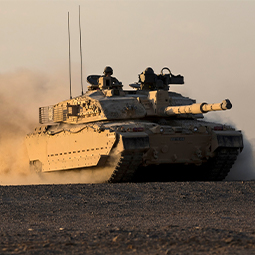 British Challenger 2 MBT glides effortlessly across the soft sand with the low evening light glinting off the desert camouflage.