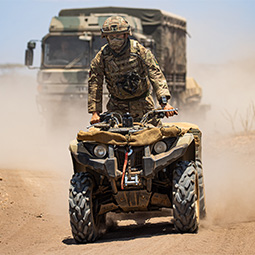 Soldier from 2 Rifles mortar platoon rides a Grizzly 450 Quad Bike (followed by a Man SV Truck).